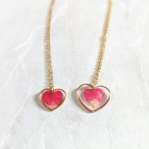 two dainty heart necklace swith real rose petals inside. one is smaller and one is larger