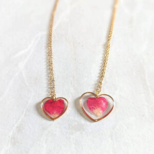 two dainty heart necklace swith real rose petals inside. one is smaller and one is larger