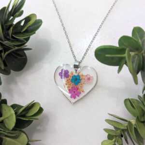 a silver heart-shaped necklace with real flowers inside