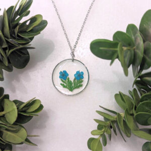 a circle frame necklace with real pressed flowers and leaves inside