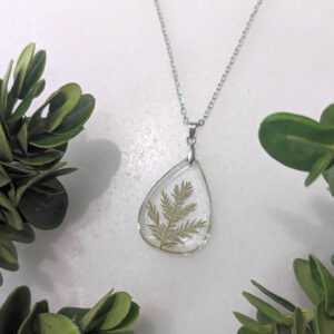 a frameless clear teardrop necklace with a real cedar foliage inside