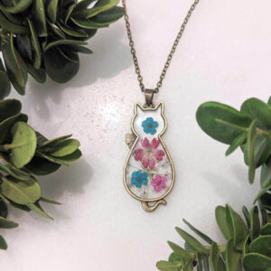 a bronze cat necklace with a bouquet of real pressed colorful flowers inside