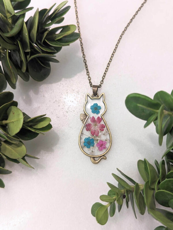 a bronze cat necklace with a bouquet of real pressed colorful flowers inside